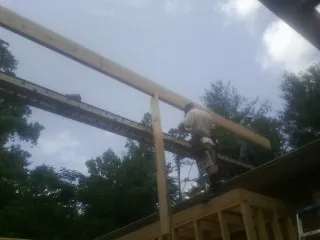 Carpenter setting a ridge beam over a new addition frame — Ice Dam Removal by Roofing Brothers in Mabelvale