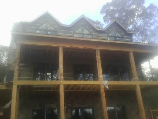 Dormers and porch framing on a large log home under construction — Roof Coating work by our crew in Mabelvale