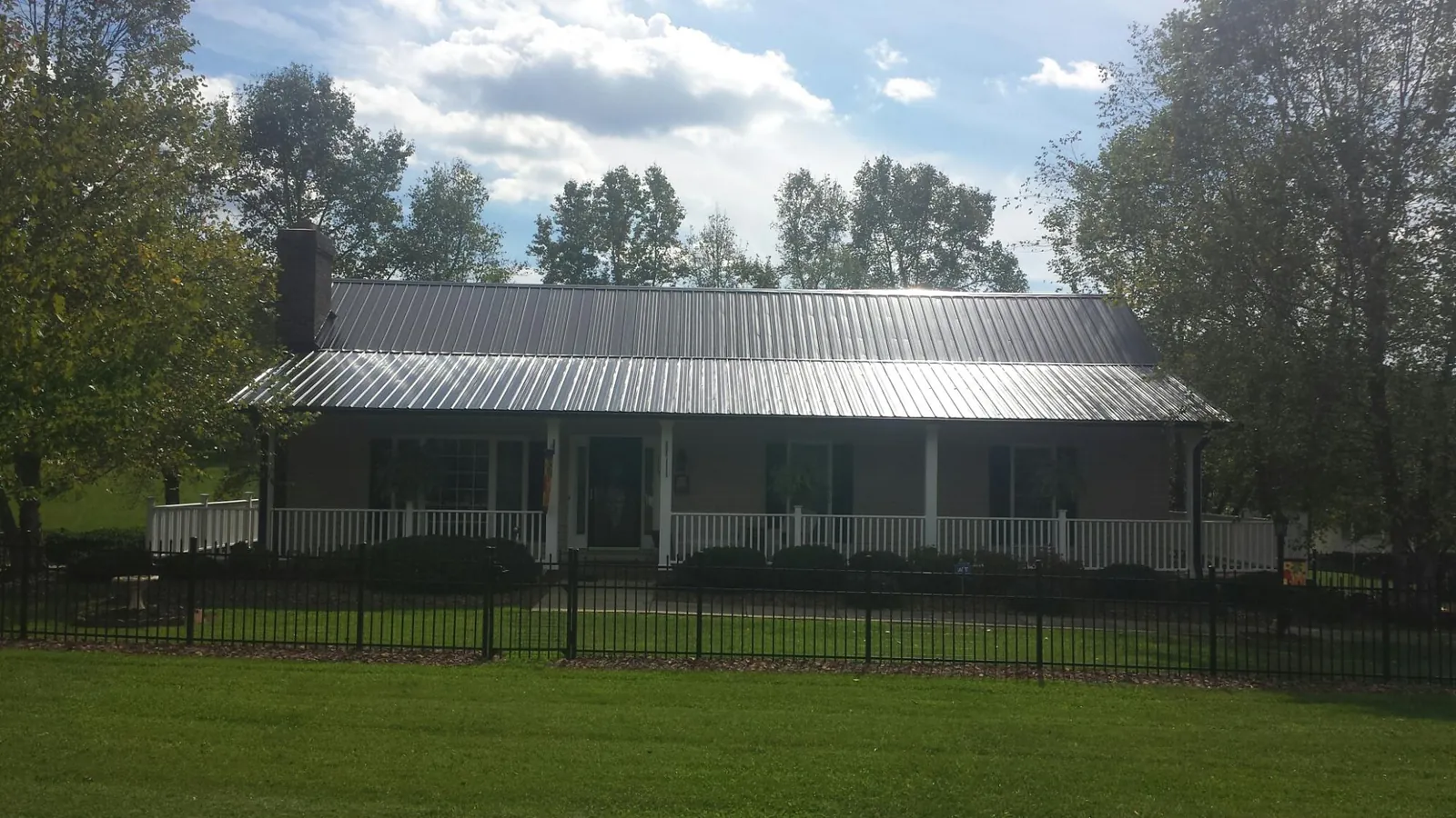 Gray metal roof on a brick ranch with a full width front porch — Gutter Guard Installation work by our crew in Mabelvale