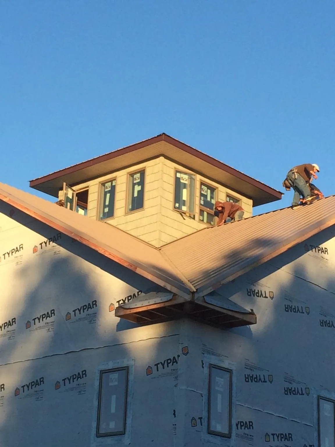 Roofers working around a rooftop cupola on a new metal roof at sunset — Roof Waterproofing in Mabelvale by Roofing Brothers